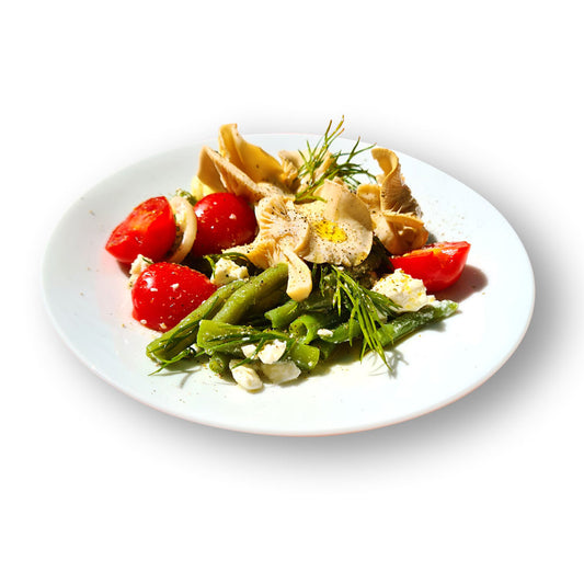 Salat mit grünen Bohnen, Cocktailtomaten, Feta und Limonenseitlingen auf weißem Teller